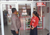 Salah satu Bhabinkamtibmas Polres Sidrap memasang stiker 110 di toko masyarakat setempat.