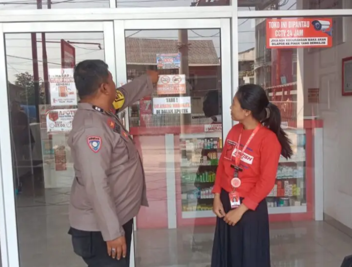 Salah satu Bhabinkamtibmas Polres Sidrap memasang stiker 110 di toko masyarakat setempat.